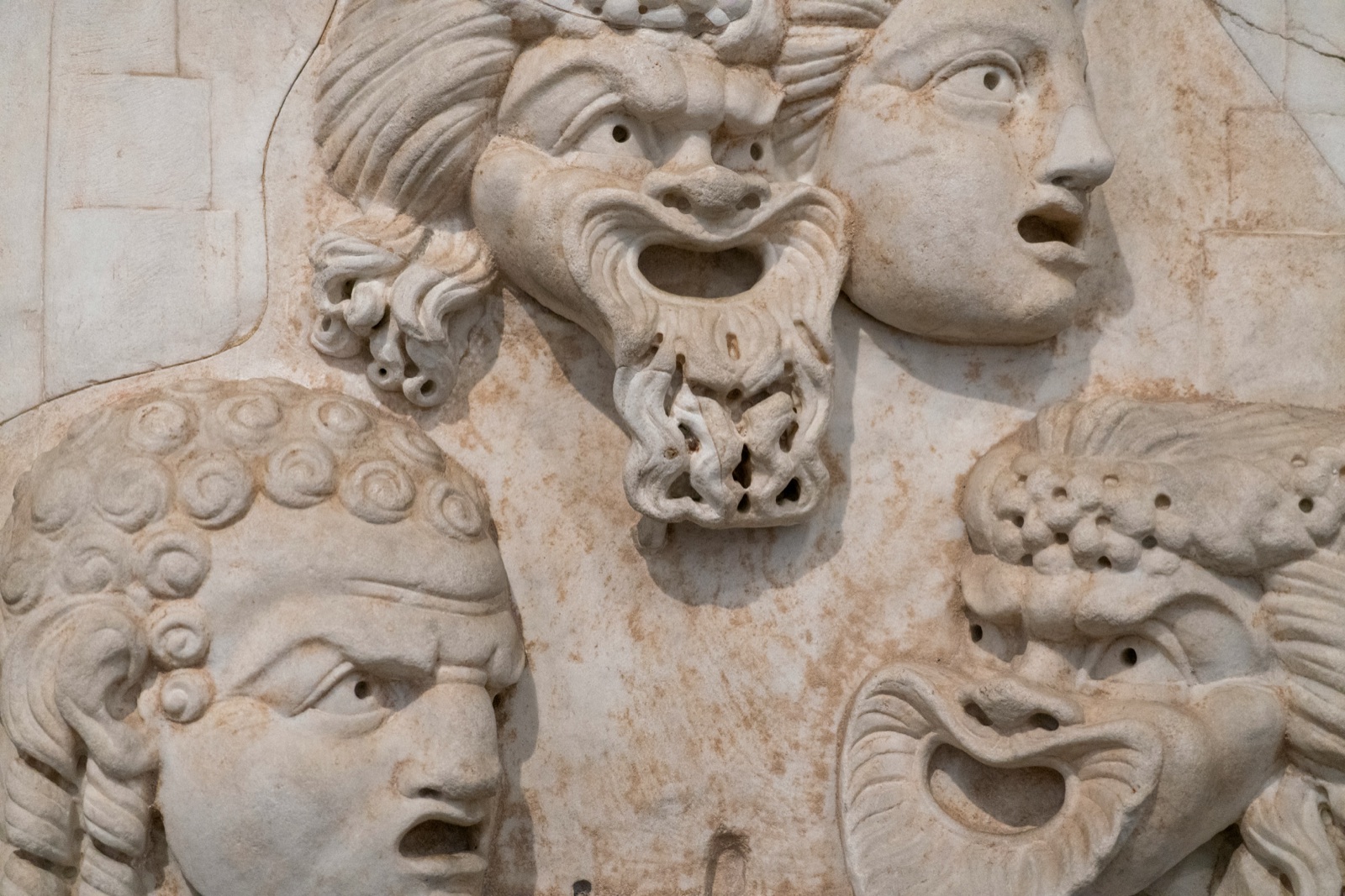 A carved stone relief showing several contrasting human expressions.